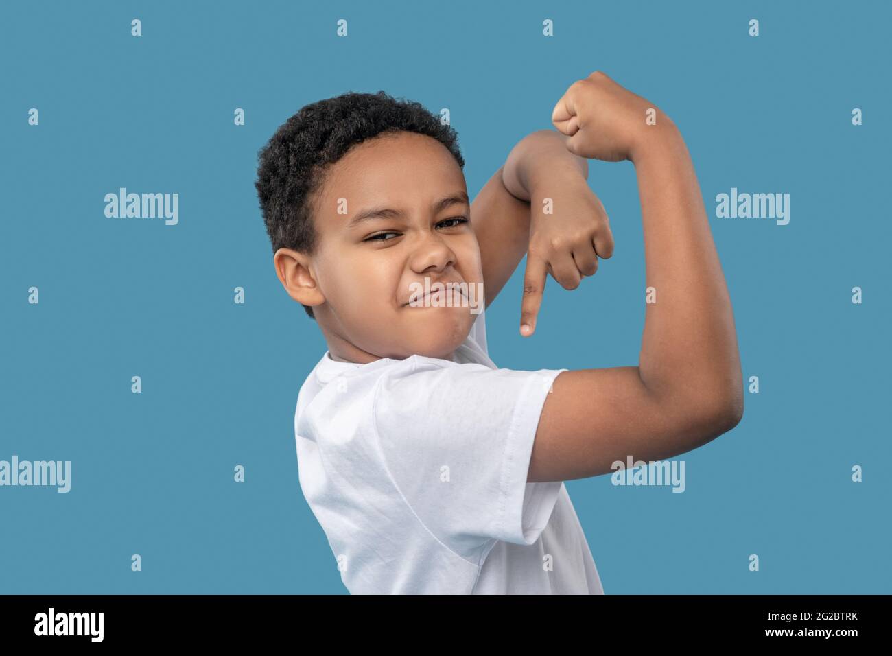 Funny cute boy showing off his muscles Stock Photo Alamy