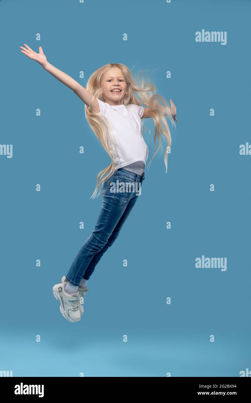 Girl jumping upwards with her hands to sides Stock Photo