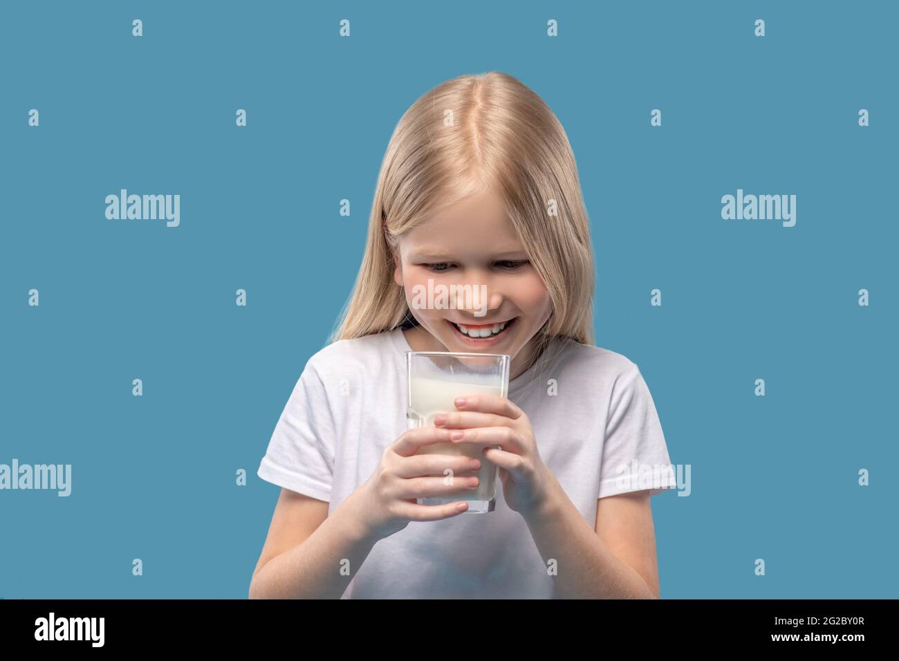 Happy delighted girl looking at glass of milk Stock Photo
