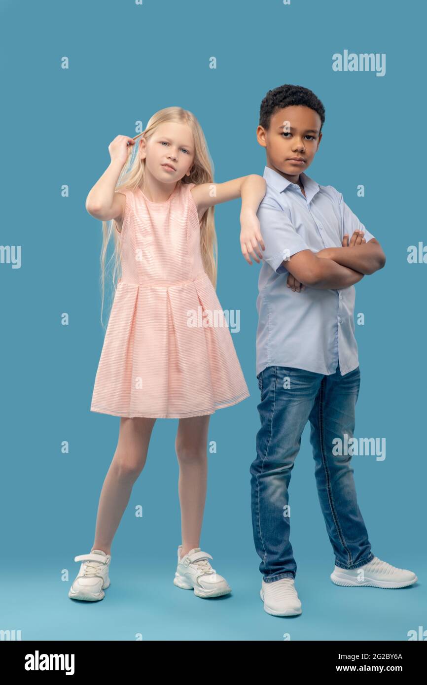 Primary school girl and boy standing on blue background Stock Photo - Alamy