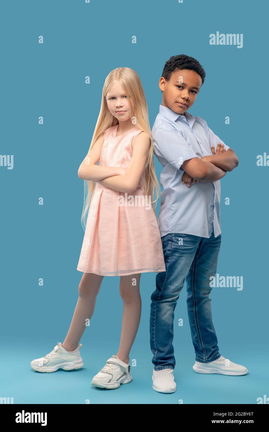 Caucasian girl and darkskinned boy standing with folded hands Stock Photo