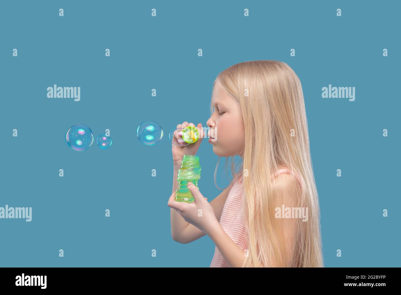 Girl standing sideways making soap bubbles Stock Photo