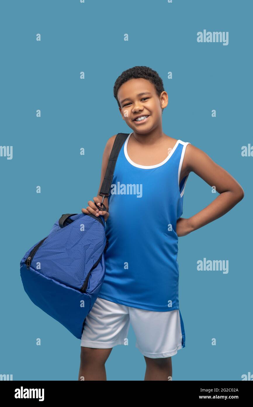 Happy dark skinned boy with gym bag Stock Photo