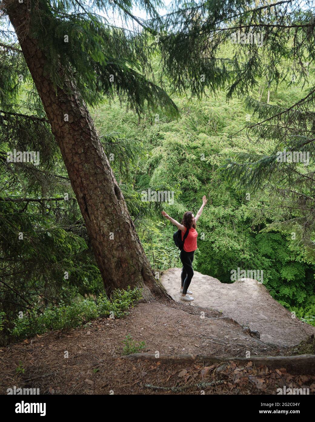 A girl with a backpack stands on the edge of a cliff. Travel outside