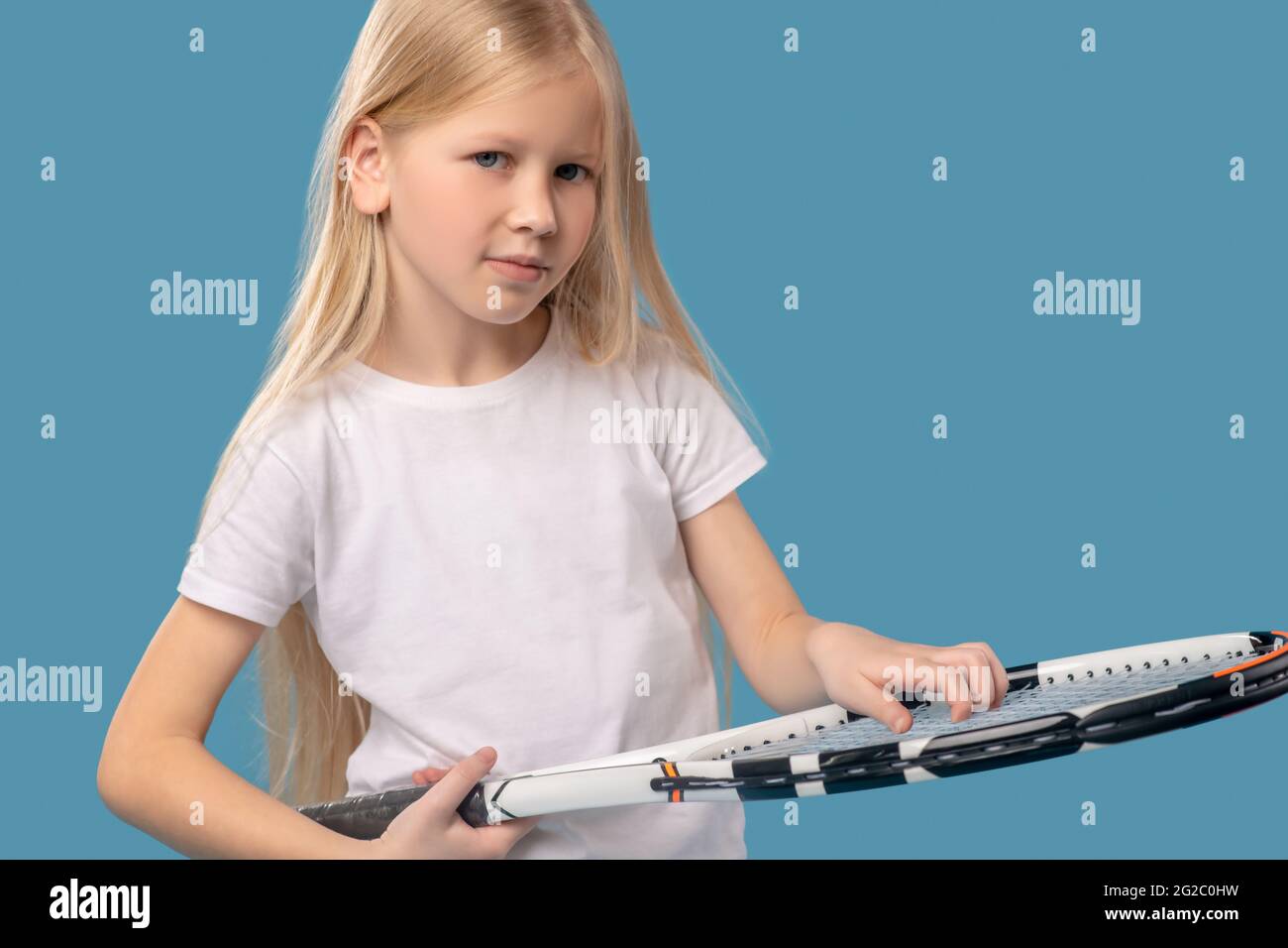Girl touching stringarea face of tennis racket with fingers Stock Photo