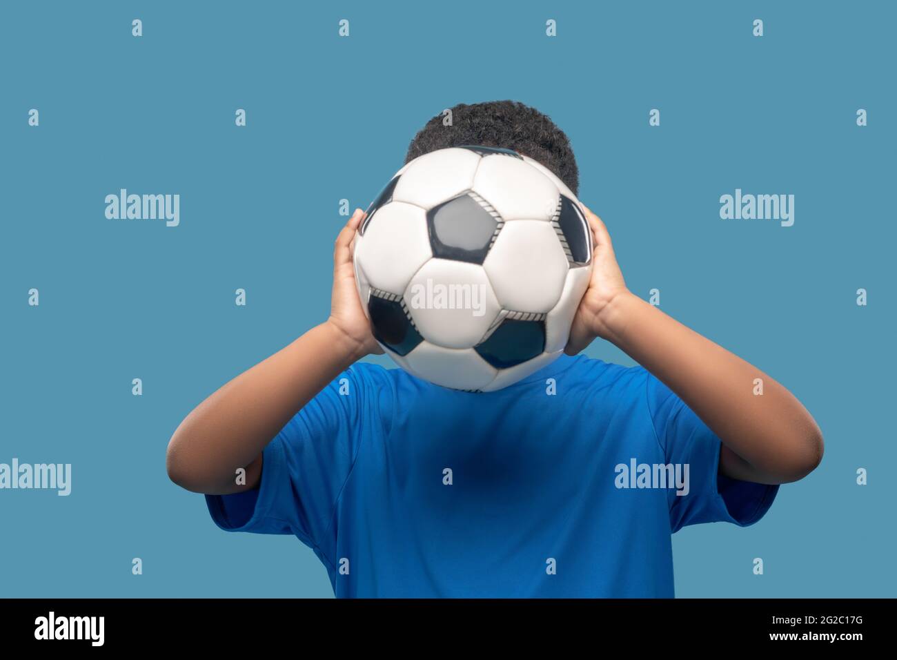 Boy holding soccer ball at face level Stock Photo