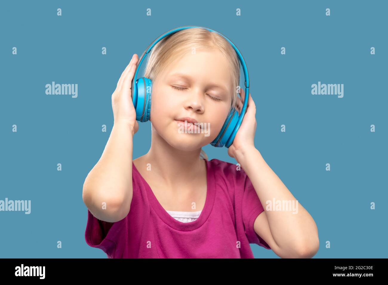 Primary school girl with closed eyes wearing headphones Stock Photo