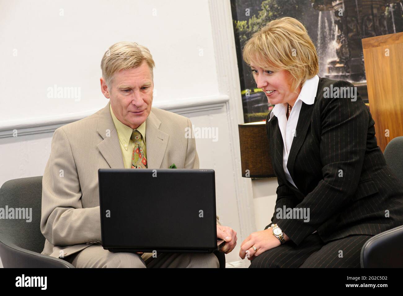 Man and woman consulting a laptop during a business meeting. Stock Photo