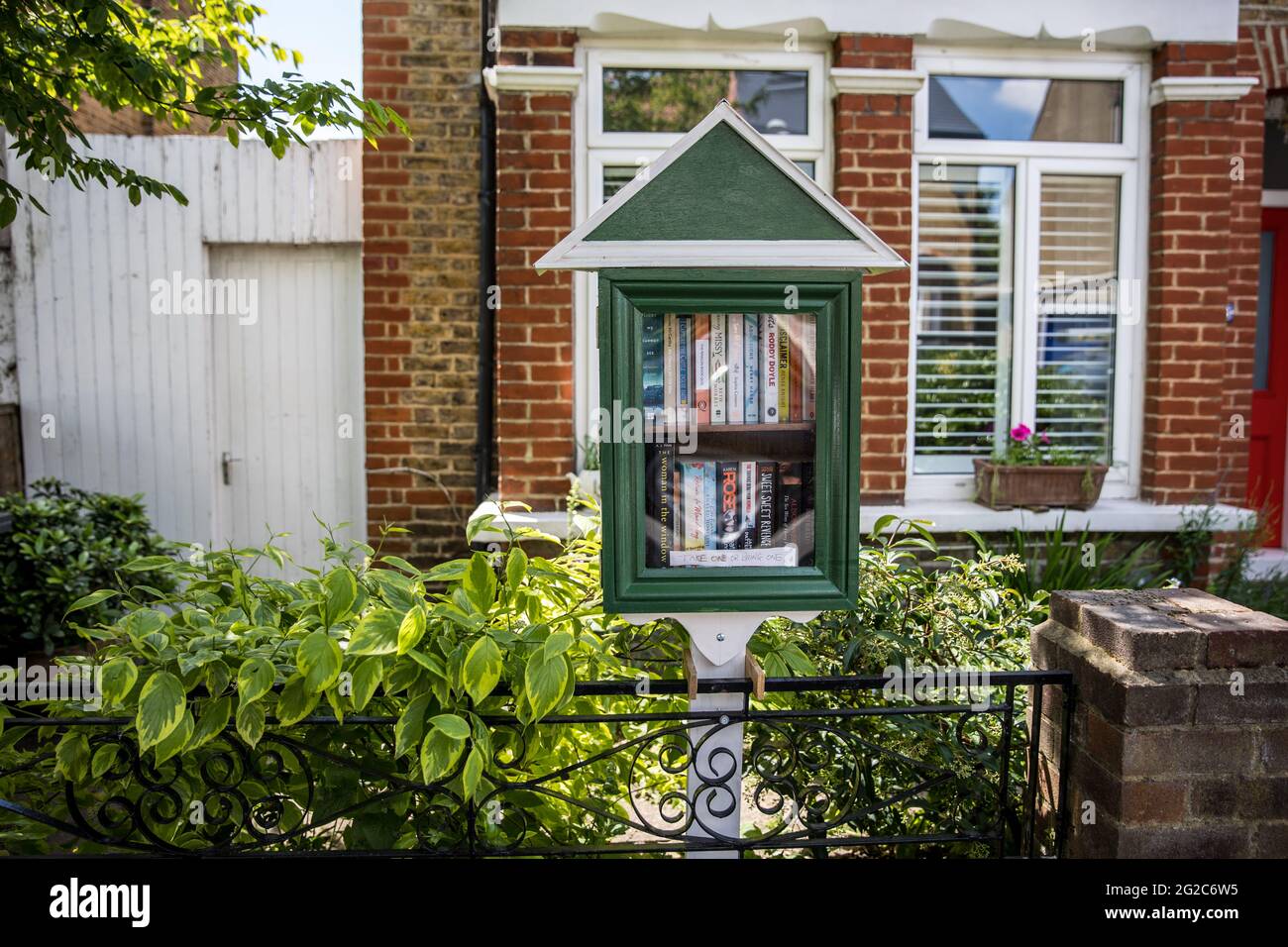 Book sharing cabinet outside a house in South London. Stock Photo