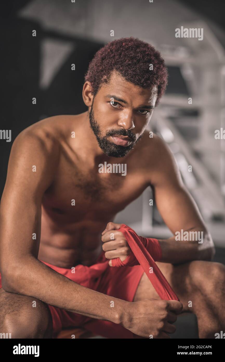 Dark-skinned young sportsman in a gym getting ready for the workout Stock Photo