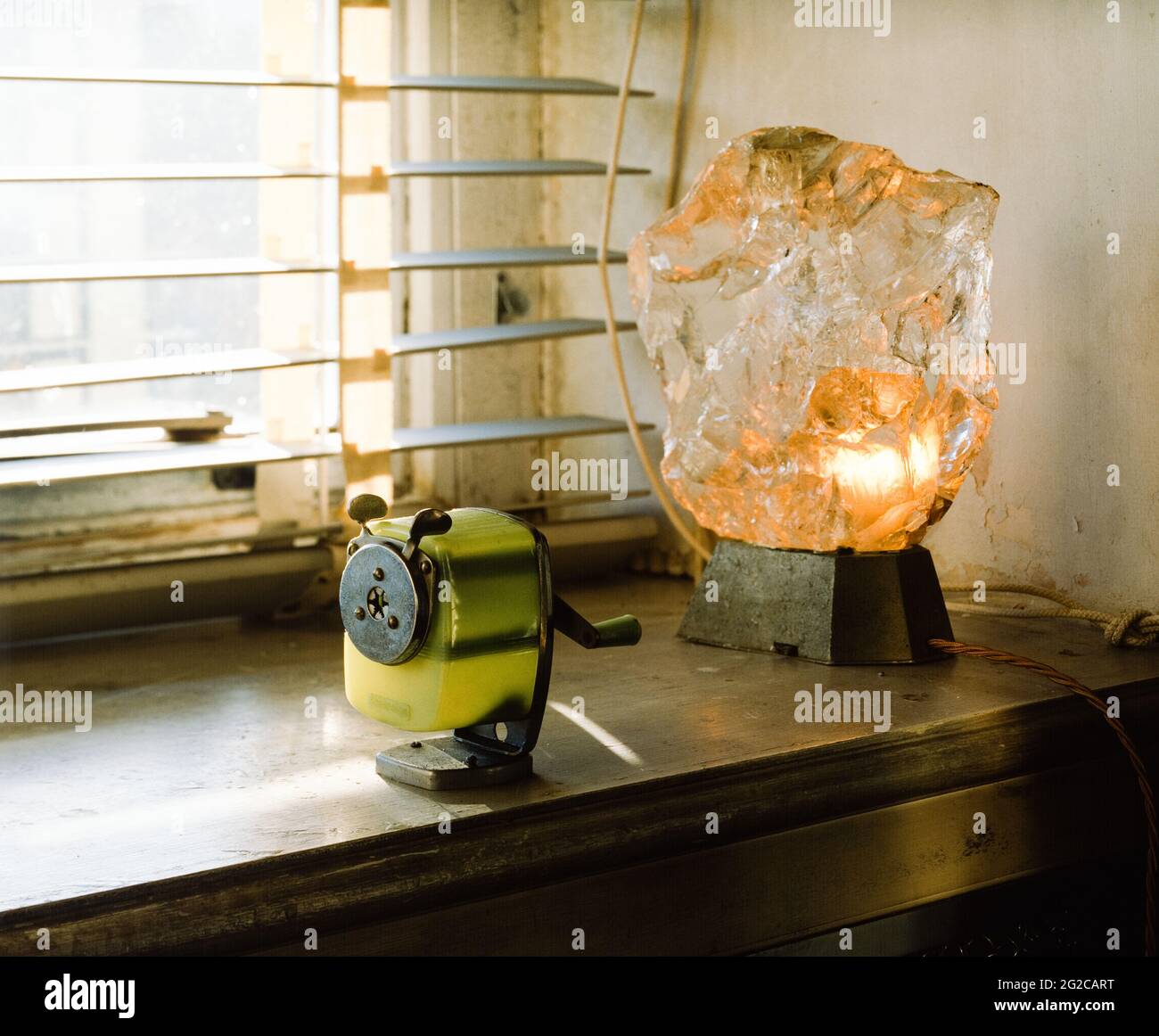 Lit crystal lamp and pencil sharpener on window sill Stock Photo
