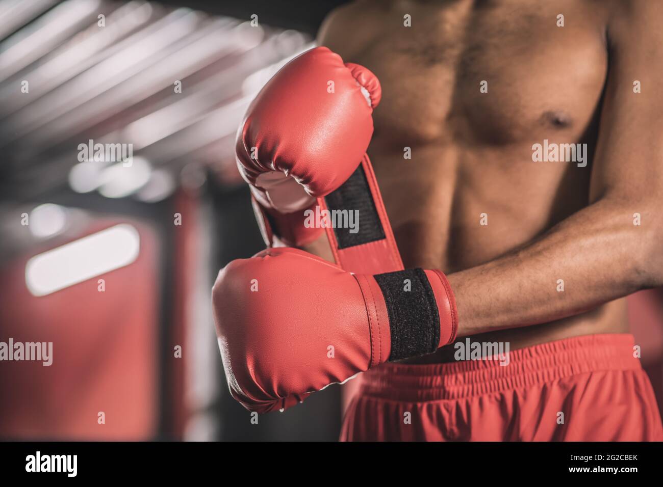 Dark-skinned kickboxer in red shorts and red boxing gloves Stock Photo