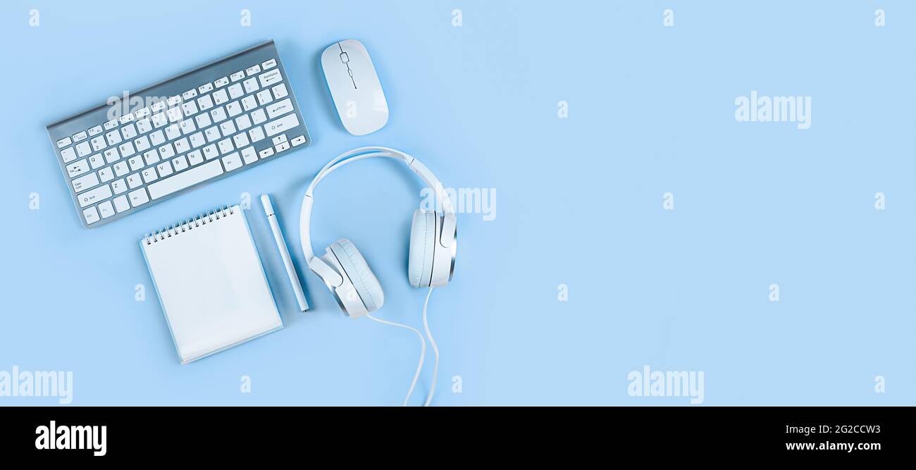 Wide banner on a light blue background, flat layout, keyboard, headphones, notebook, smartphone. Concept - home office, online education, webinars Stock Photo