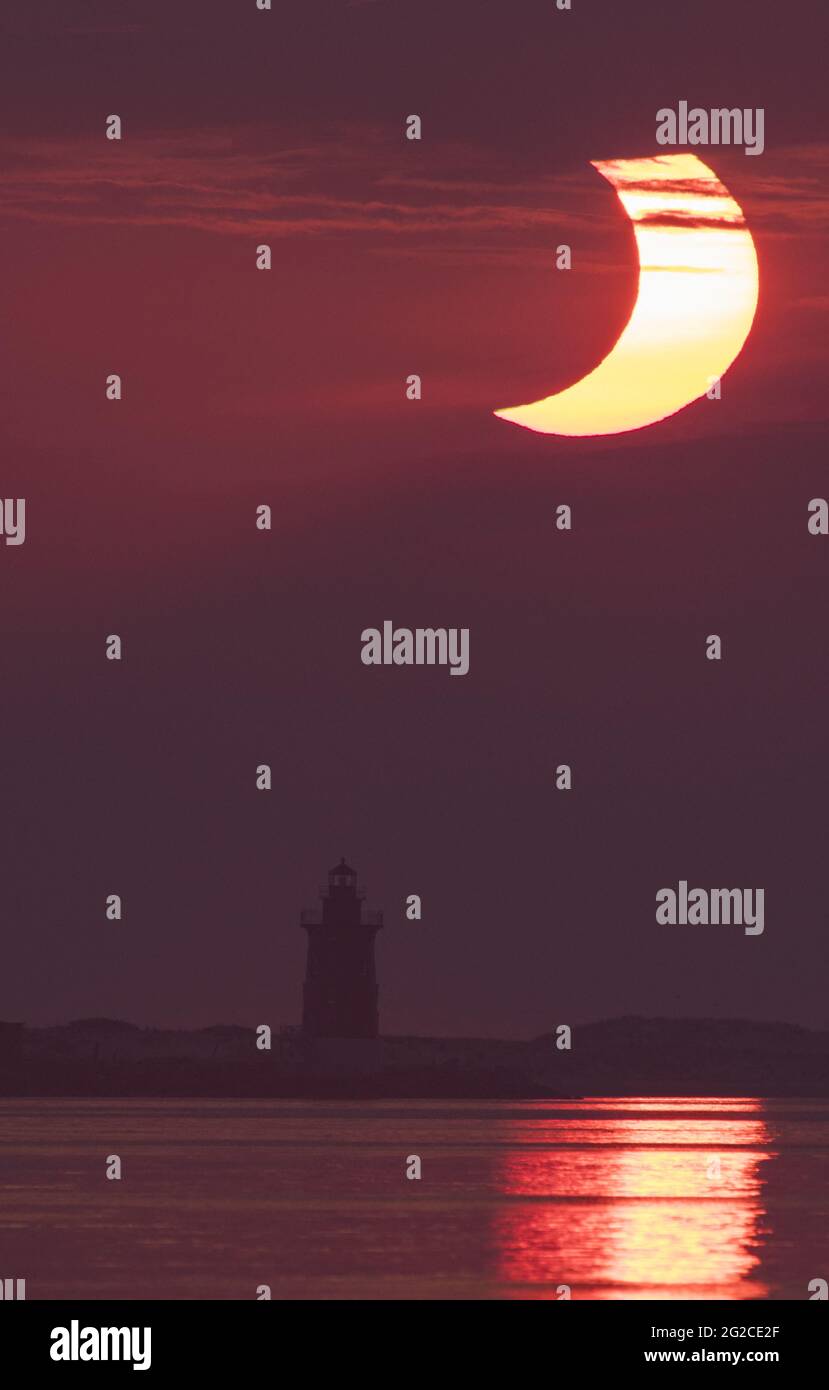 A partial solar eclipse is seen as the sun rises behind the Delaware Breakwater Lighthouse, Thursday, June 10, 2021, at Lewes Beach in Delaware. The annular or âÂ€Âœring of fireâÂ€Â solar eclipse is only visible to some parts of Greenland, Northern Russia, and Canada.Photo by Aubrey Gemignani / NASA via CNP/ABACAPRESS.COM Stock Photo