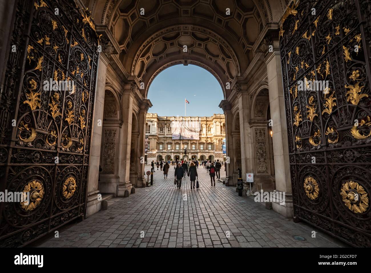 The Royal Academy of Arts, London, England. A wide view through the gates of the RA with exhibition posters for Anthony Gormley and Lucian Freud. Stock Photo