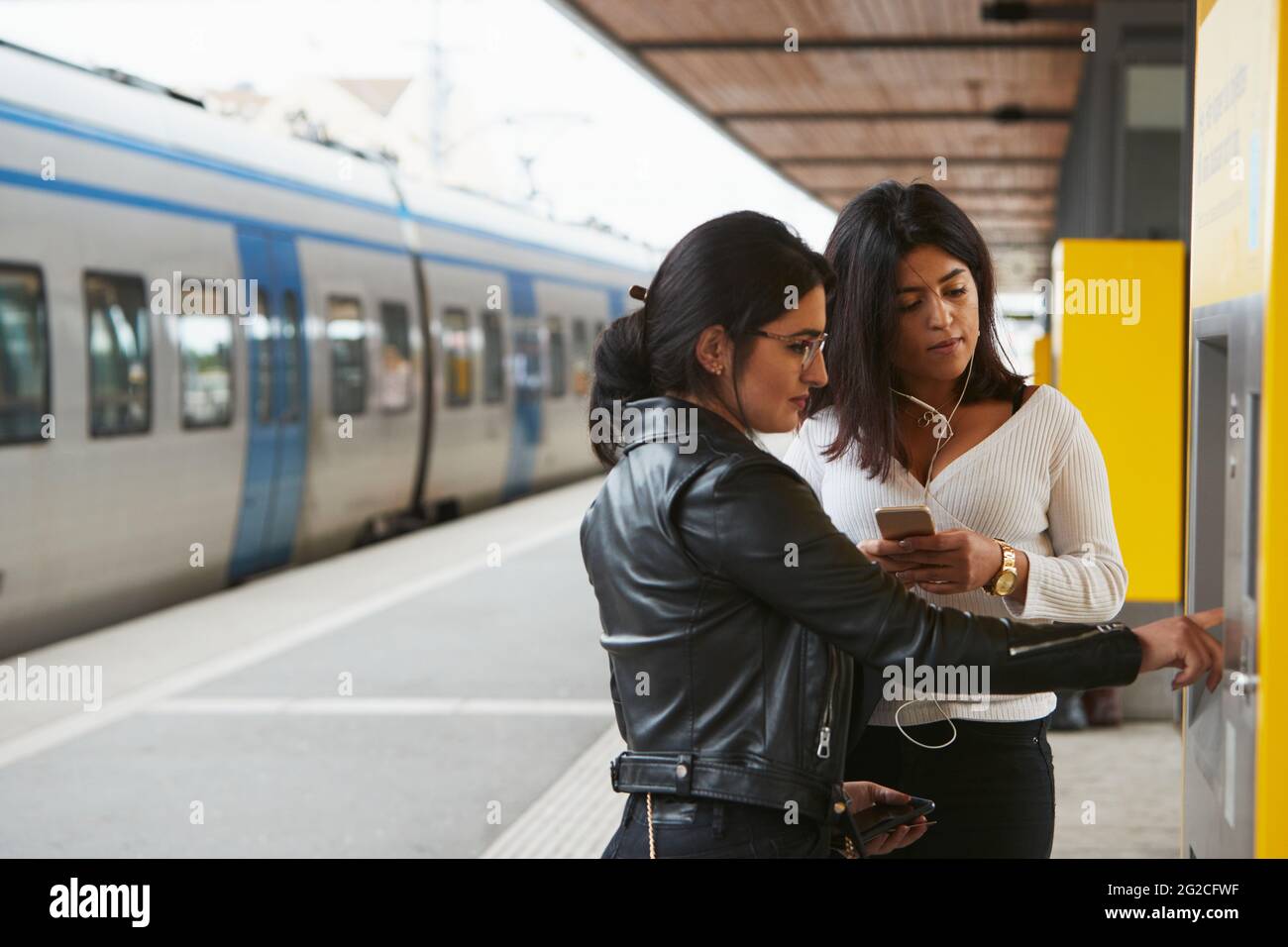Woman using ticket machine at train station Stock Photo - Alamy