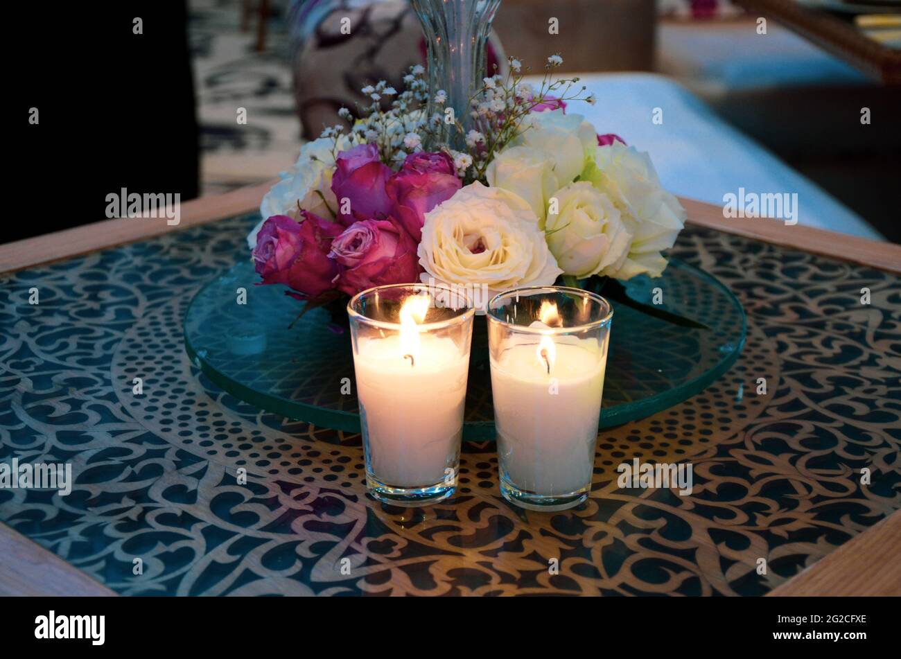 Bouquet of white flowers in a vase, candles on vintage copper tray, wedding home decor on a table Stock Photo