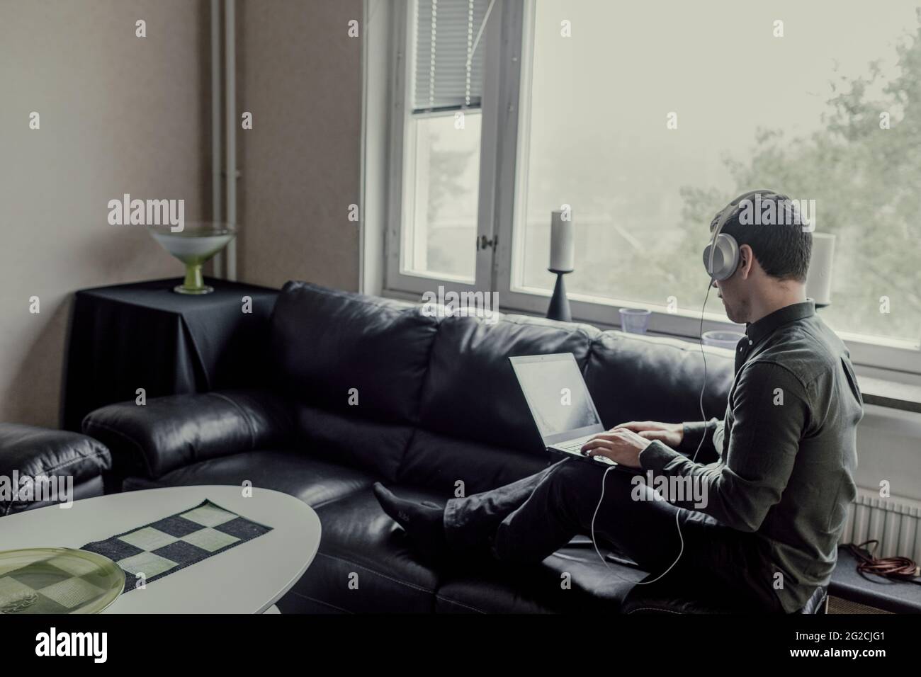 Man sitting on sofa and using laptop Stock Photo
