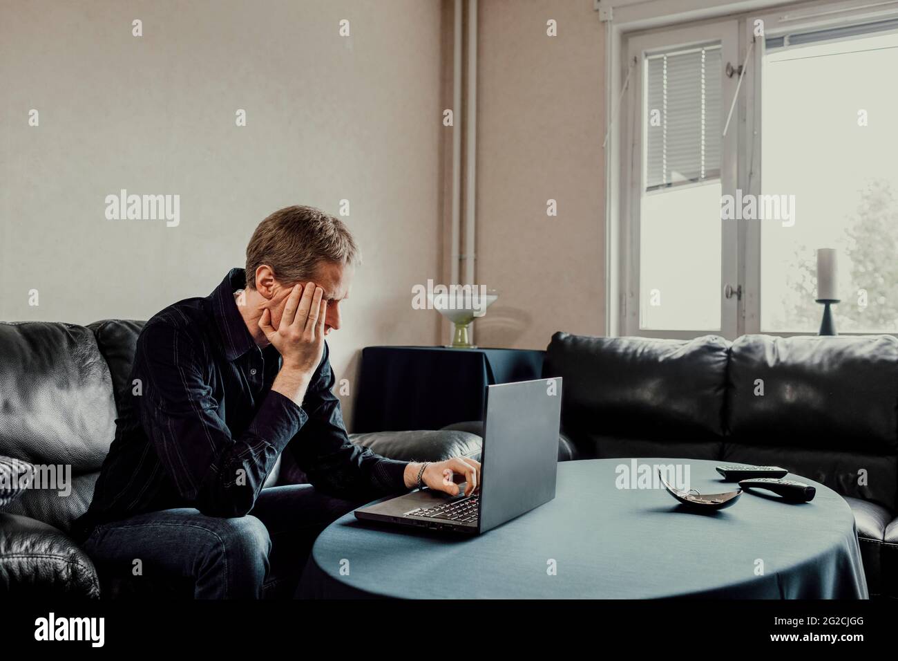 Man sitting on sofa and using laptop Stock Photo