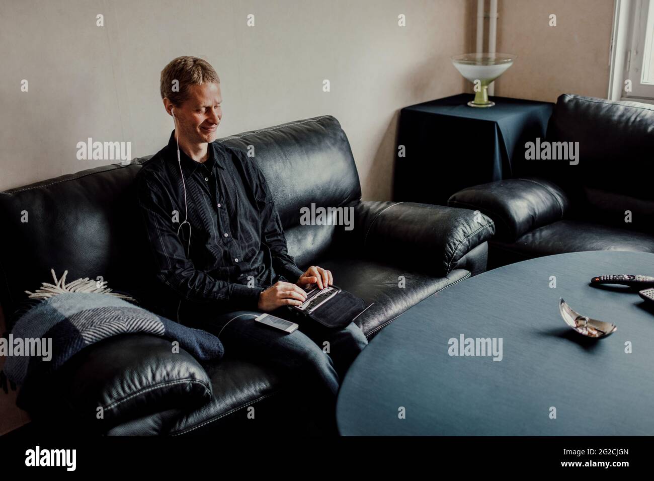 Man sitting on sofa and using Braille keyboard Stock Photo