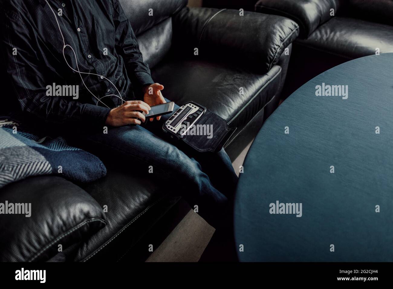 Man sitting on sofa and using Braille keyboard Stock Photo
