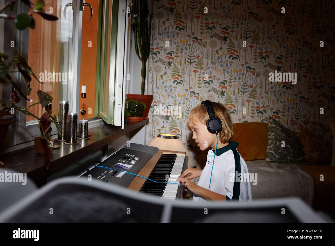 Boy wearing headphones while playing keyboard Stock Photo Alamy