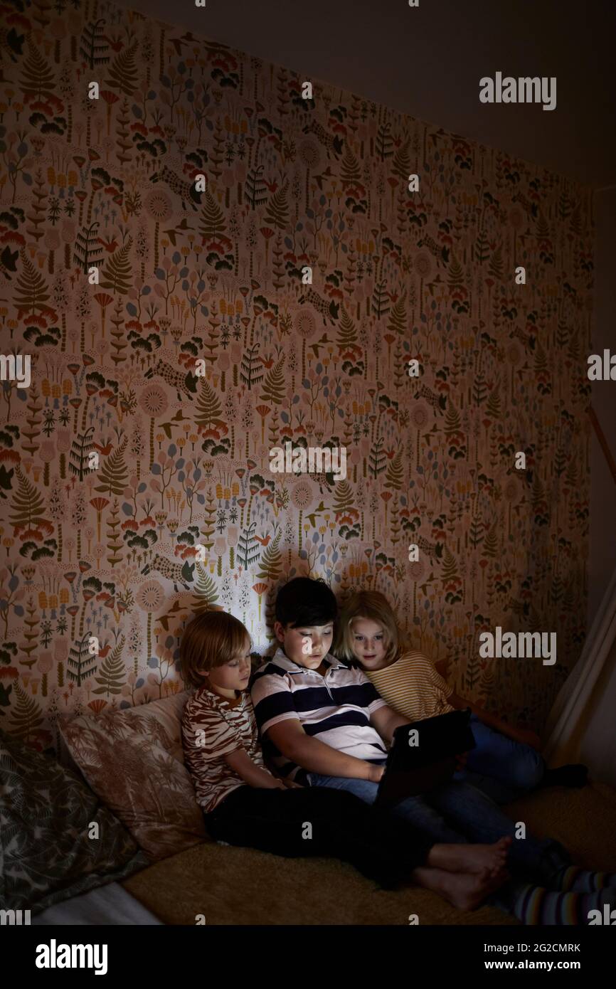 Boys using digital tablet on bed Stock Photo