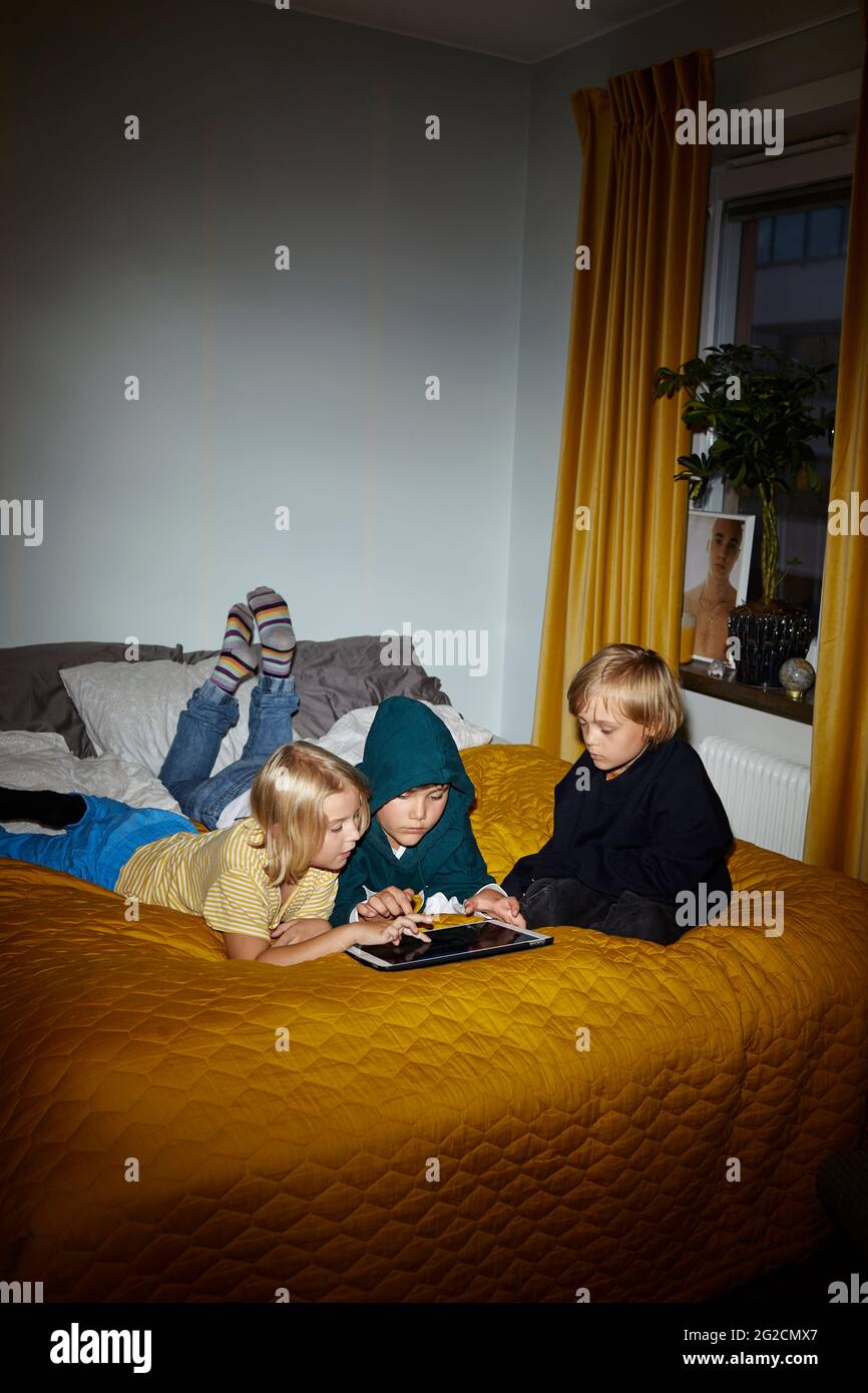 Boys using digital tablet on bed Stock Photo