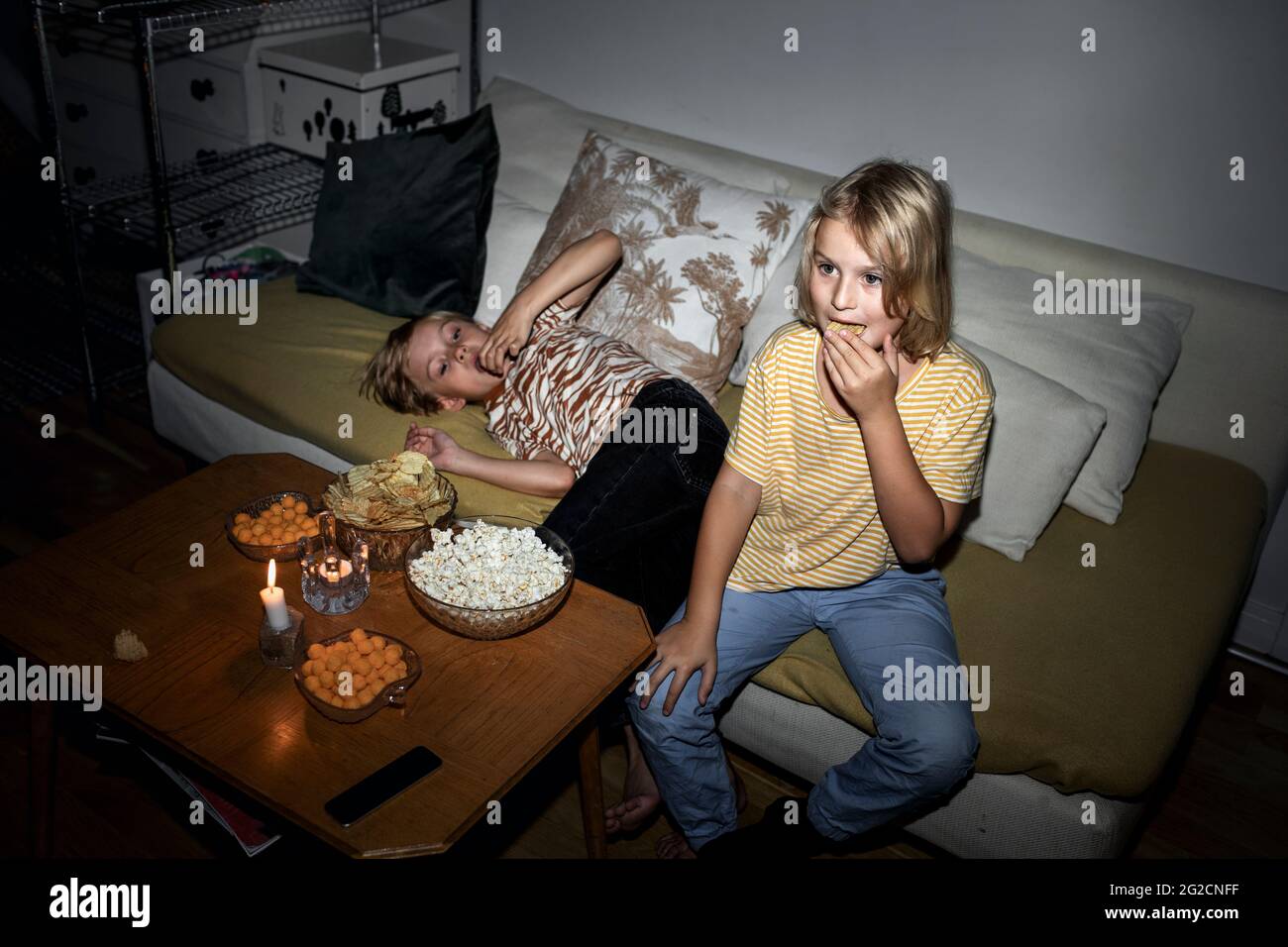 Brothers snacking on sofa Stock Photo