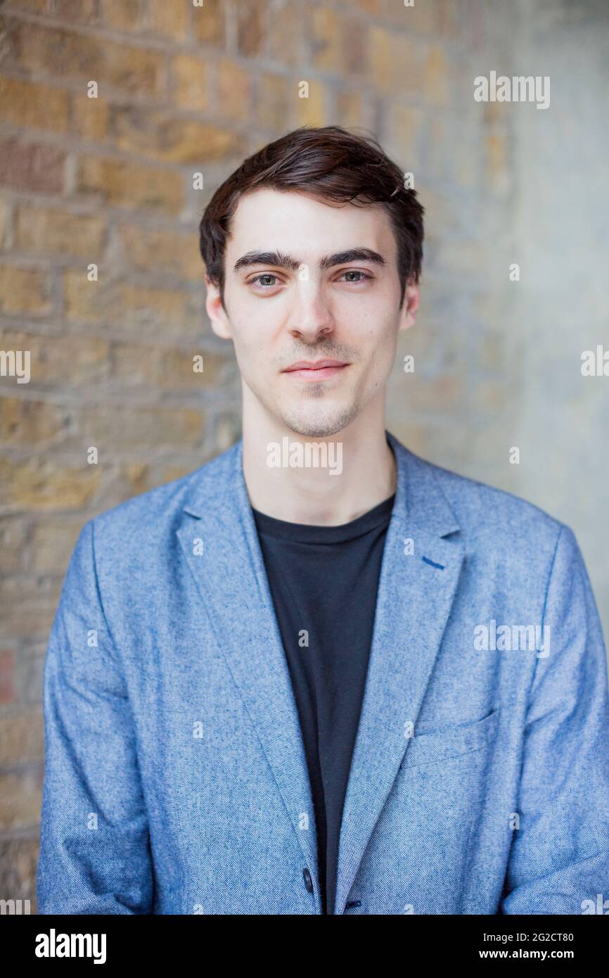 Portrait of young man against brick wall Stock Photo - Alamy