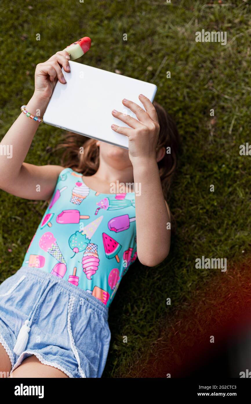 Girl lying on lawn and using digital tablet Stock Photo - Alamy