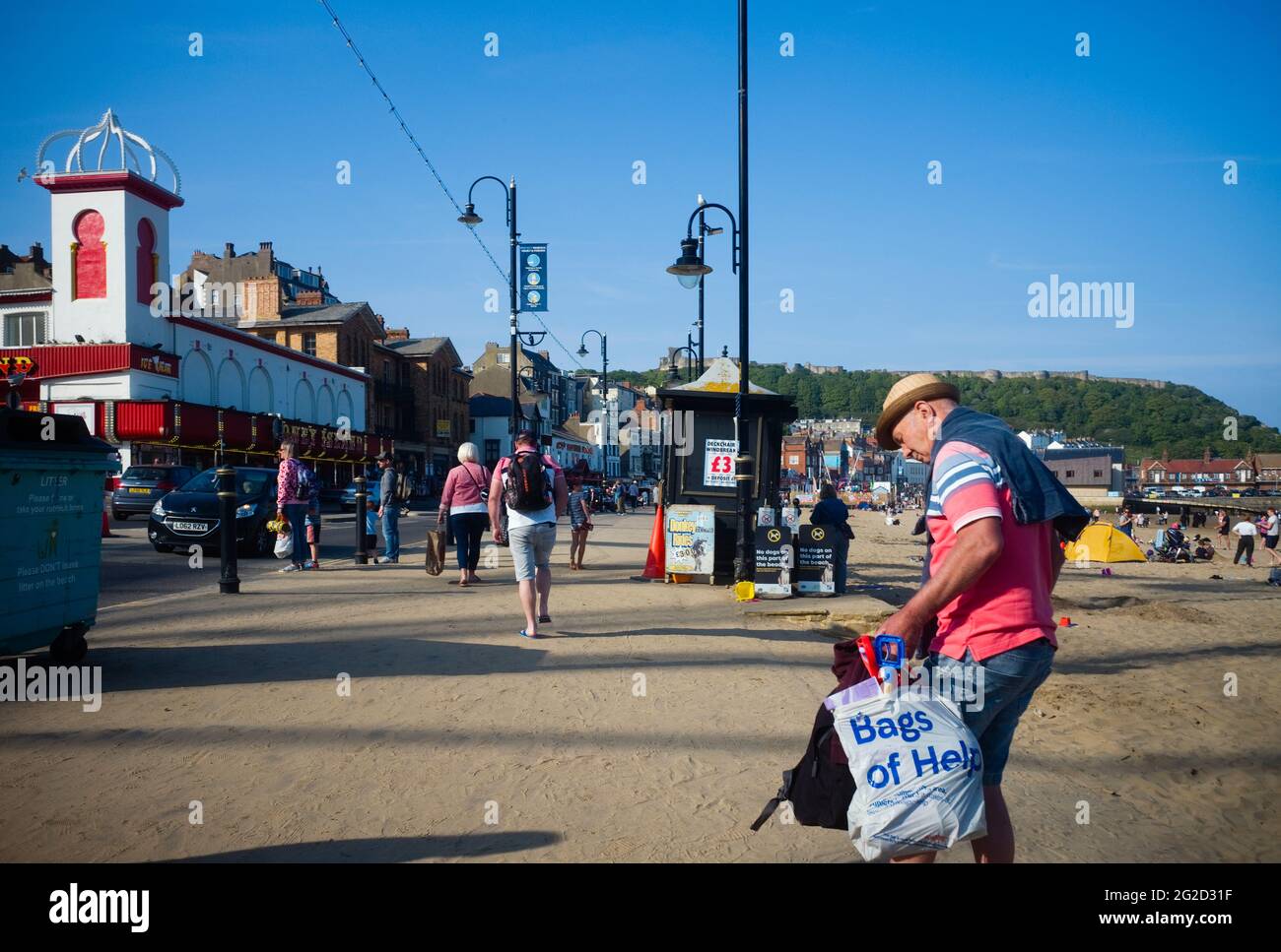 Older man struggling with a bulging bag at the seaside in Scarborough during covid times Stock Photo