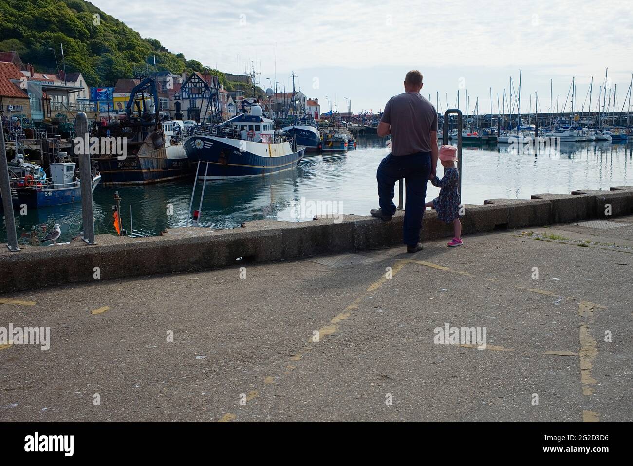 An older man showing a younger girl the fishing boats moored in Scarborough harbour Stock Photo