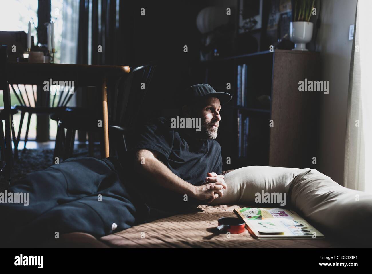 Man in baseball cap lying on floor Stock Photo