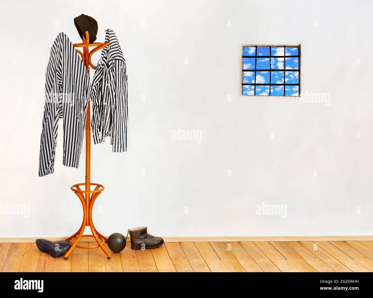 The striped prisoners costume hangs on the coat hook in an empty cell with windows with bars. Stock Photo