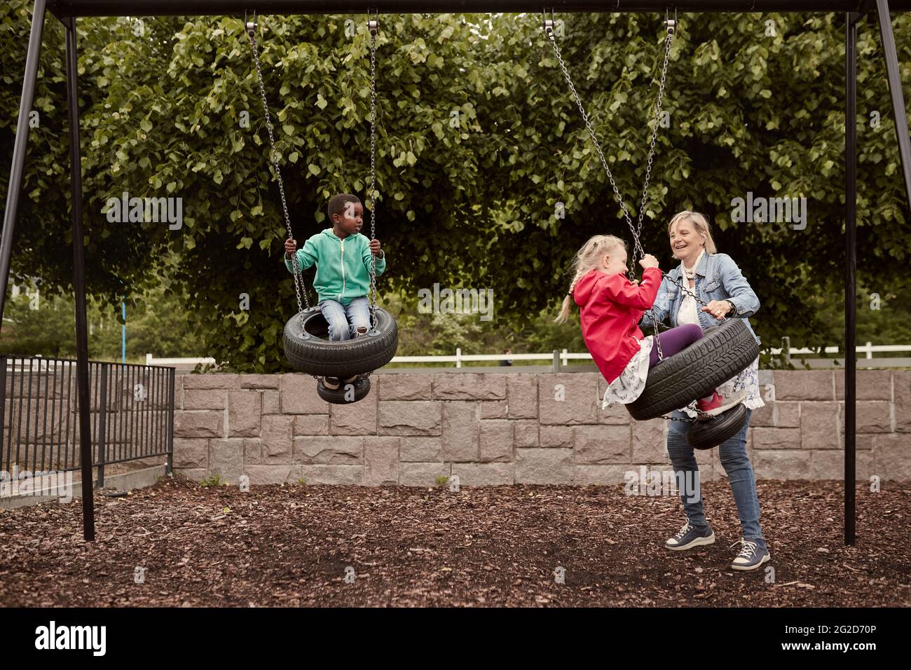Mother pushing daughter on tire swing Stock Photo