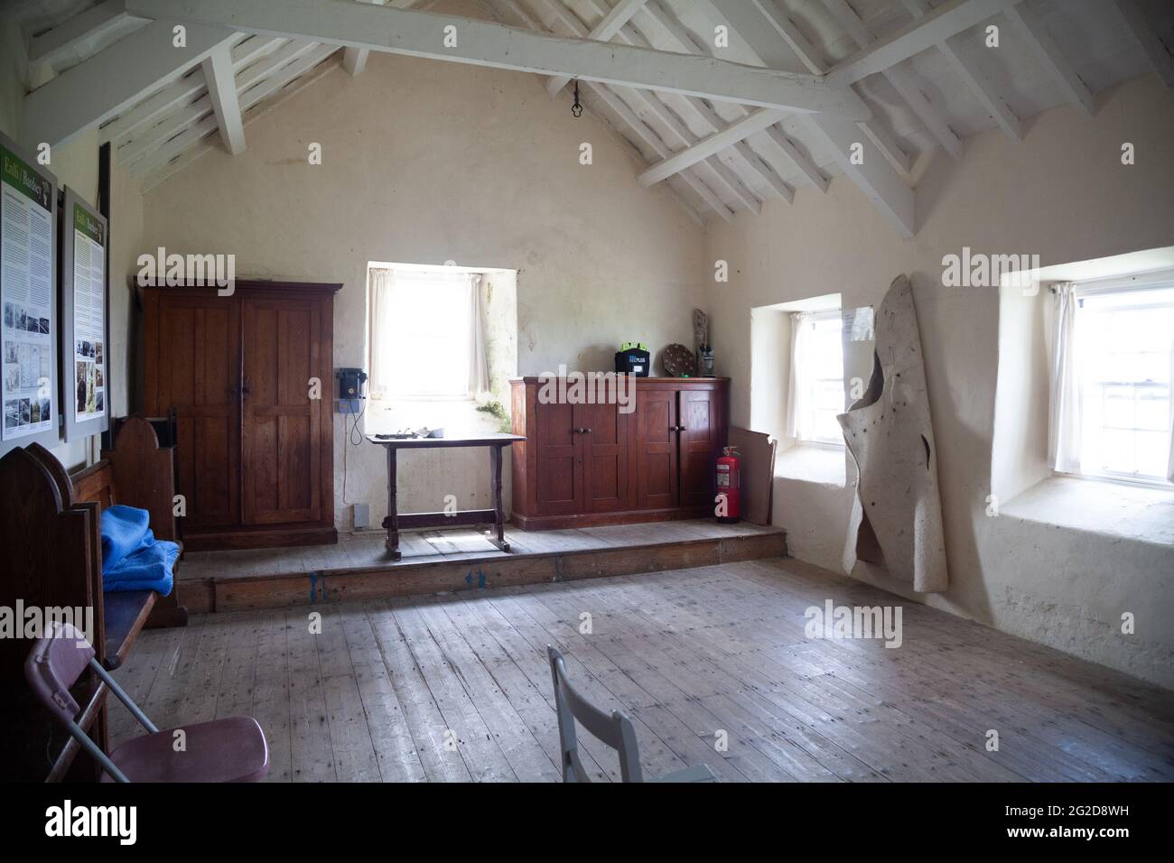 Interior of former school building on Ynys Enlli / Bardsey Island with wooden pews, cupboards, desk and wooden floor Stock Photo