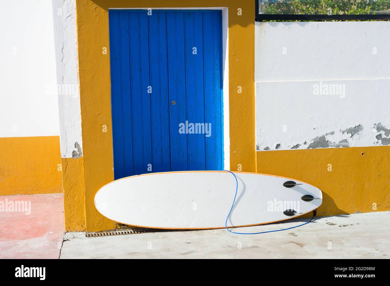 Surfboard leaning against old building wall Stock Photo