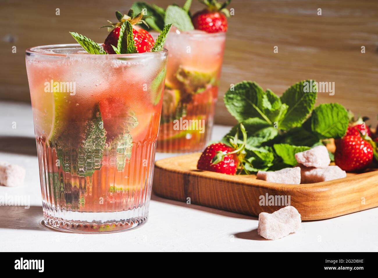 Refreshing summer drink caipirinha cocktail with strawberries and fresh mint in glasses, hard light with shadows Stock Photo