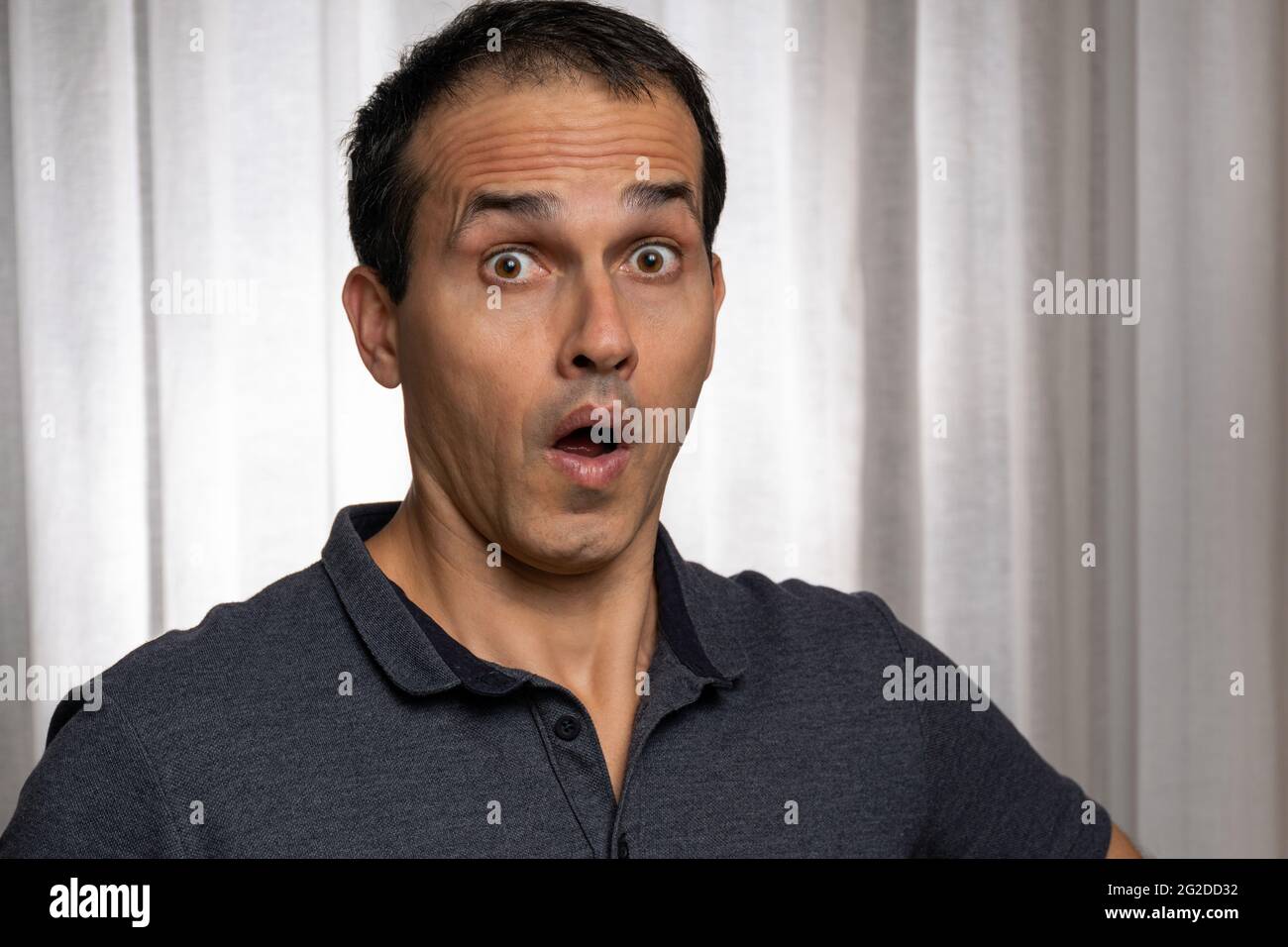Mature man (44 years old) in photo session with dark blue polo shirt, making several faces. Stock Photo