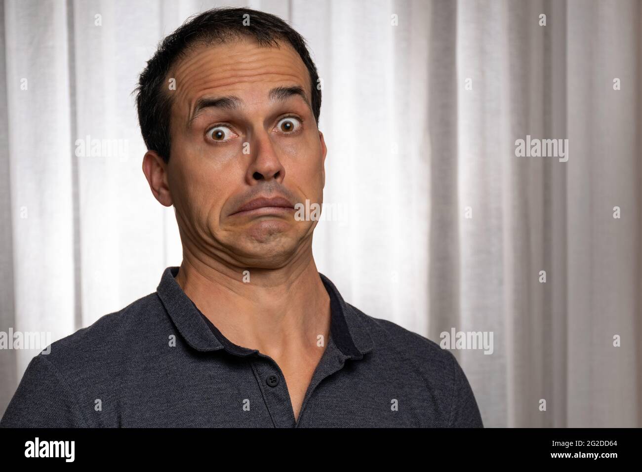 Mature man (44 years old) in photo session with dark blue polo shirt, making several faces. Stock Photo
