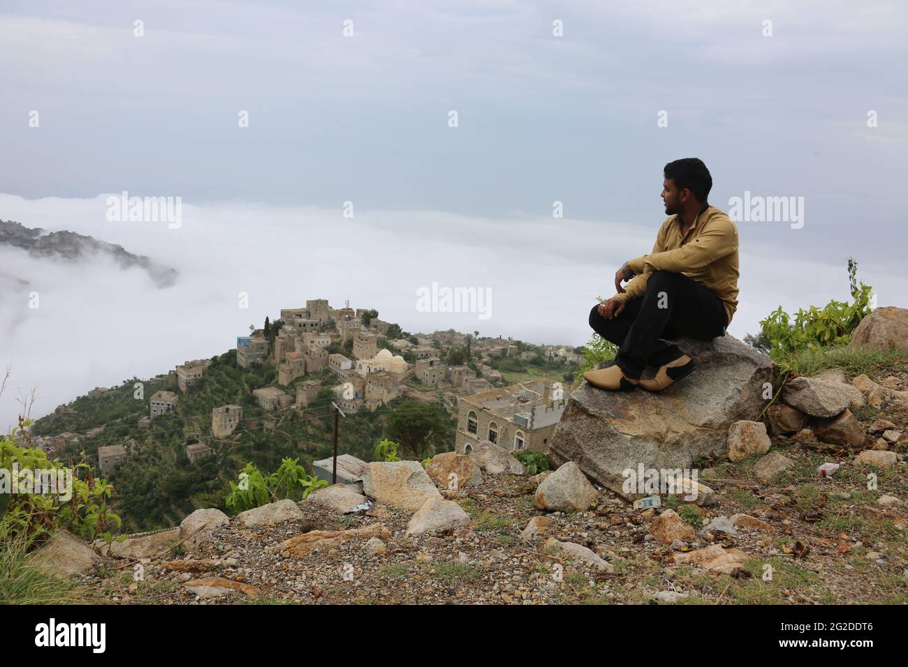 Taiz / Yemen - 04 Aug 2017 : A Yemeni sits on the top of the Sabr mountain in the Yemeni city of Taiz, and the city is cloudy Stock Photo