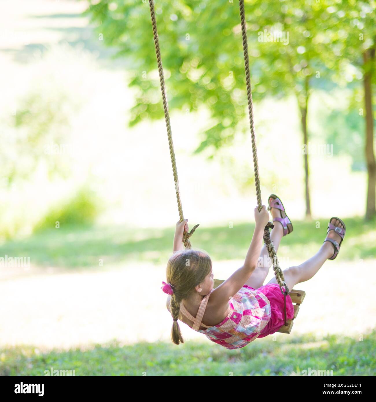 Girl Swinging on Rope Swing Stock Photo