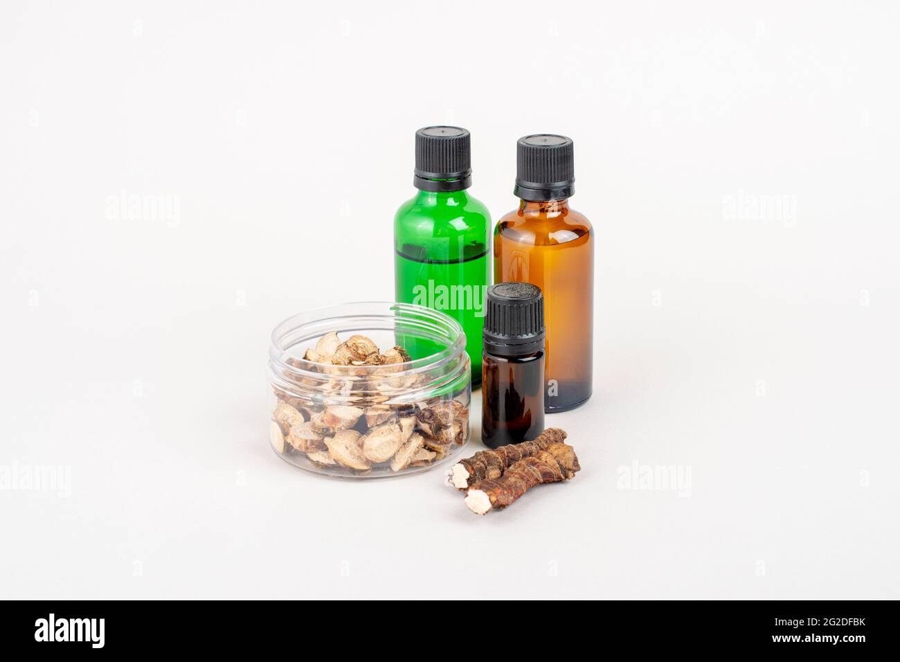 Dried Acorus calamus roots, also known as sweet flag, and bottles with oil and extract isolated on light background. For personal care products, beaut Stock Photo