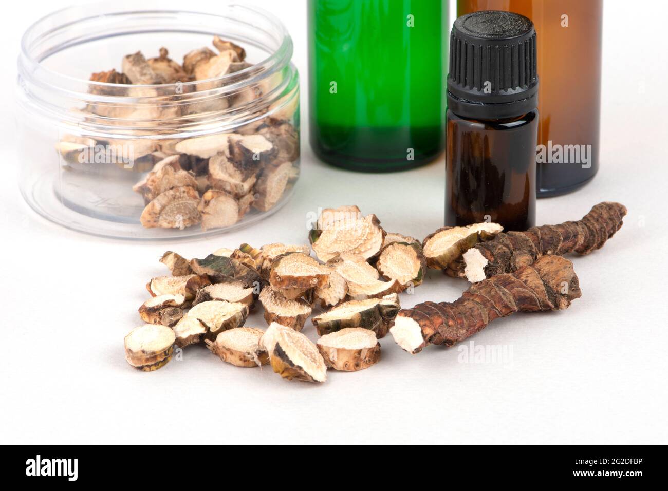 Dried Acorus calamus roots, also known as sweet flag, and bottles with oil and extract isolated on light background. For personal care products, beaut Stock Photo