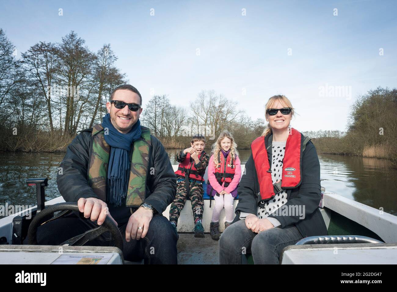 A family enjoy a day out on a hired boat on the Norfolk Broads. Stock Photo