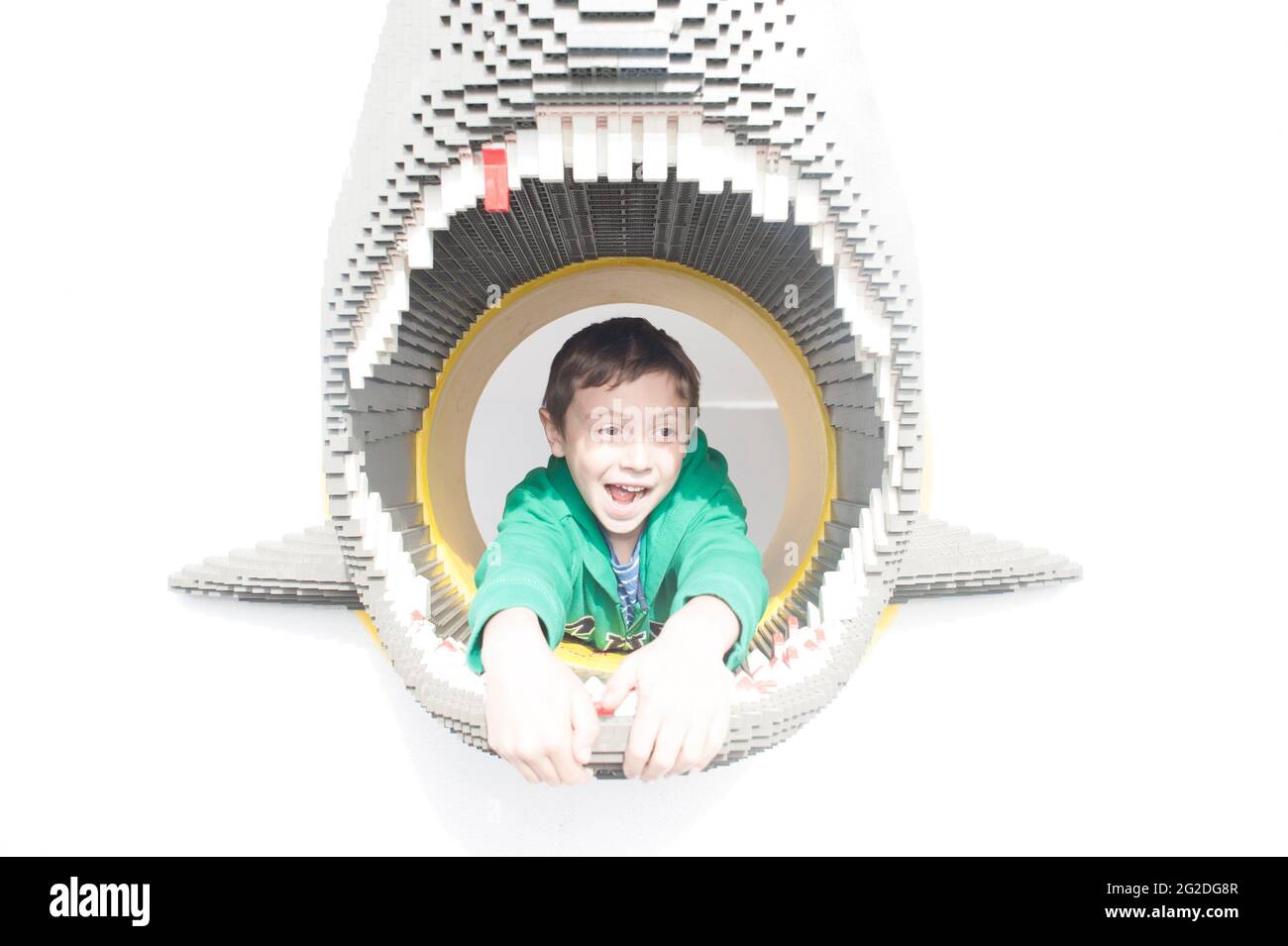 A young boy peers out of a sharks head made of Lego at Legoland in Windsor Stock Photo
