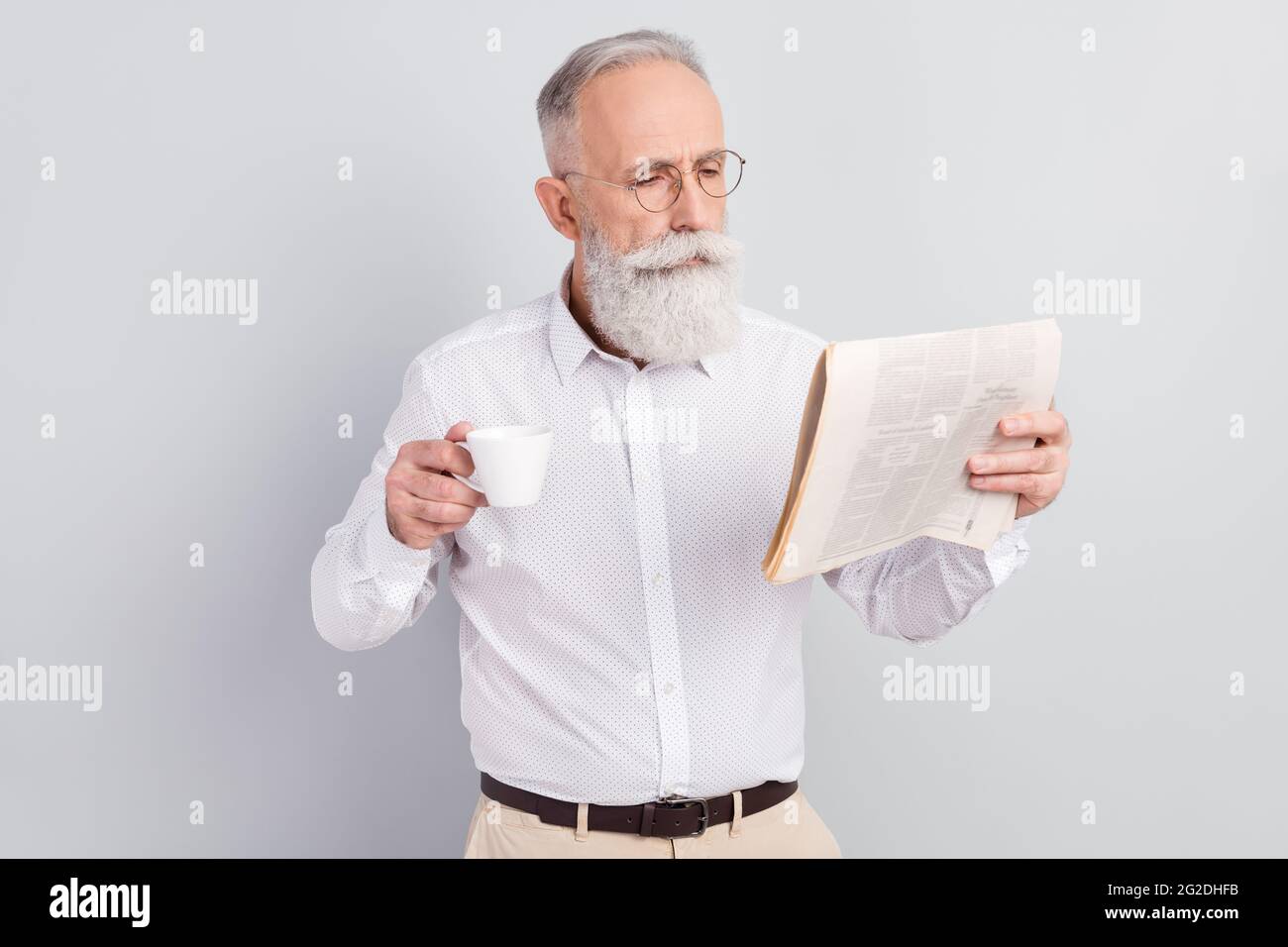 Photo of aged man read newspaper magazine news rest drink hot coffee isolated over grey color background Stock Photo