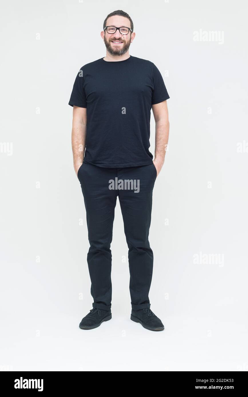 A man dressed in all black stands on a seamless white background in a photography studio Stock Photo
