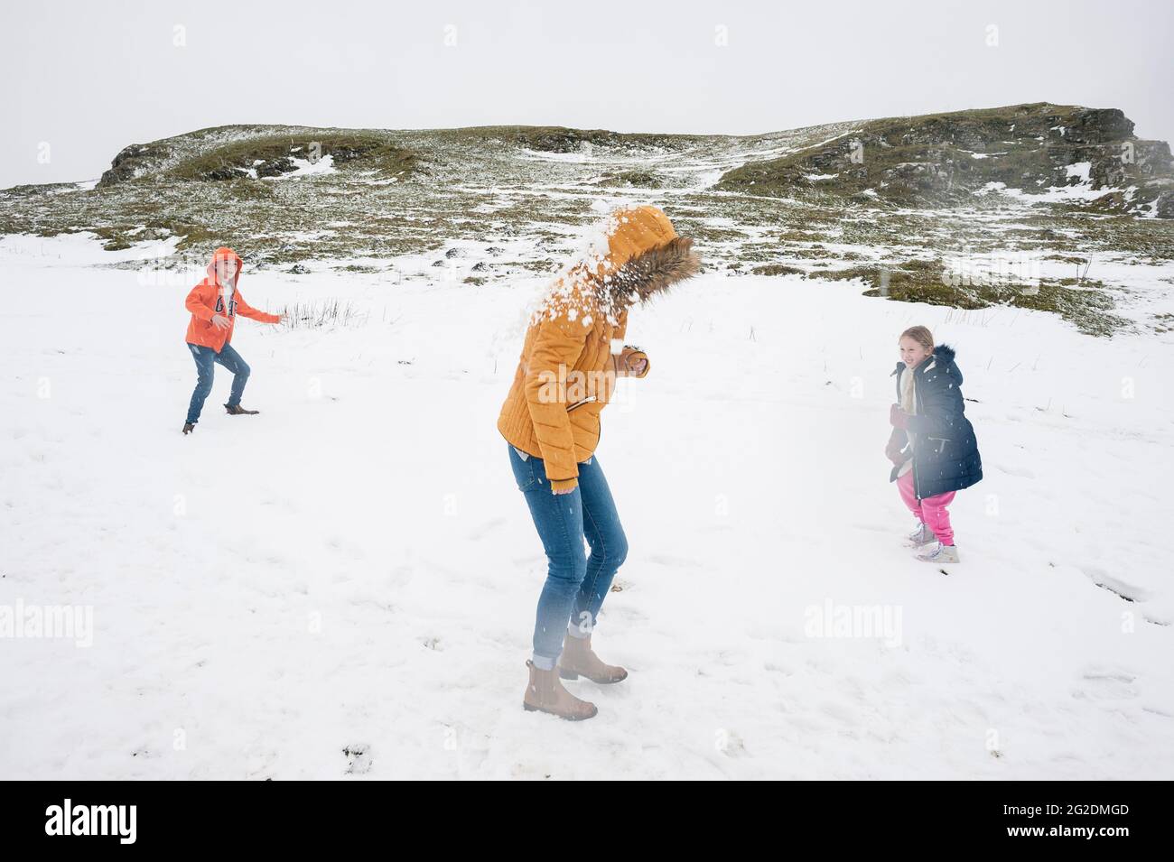 A family have fun in the cold snow which has settled on the ground. Stock Photo